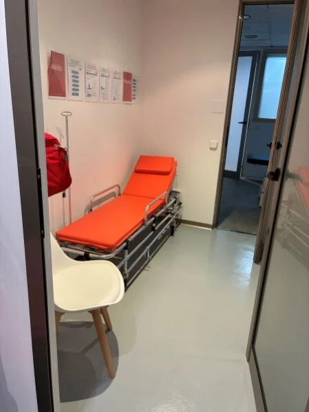 Ruheraum mit Notfallliege, Defibrillator und Zugang zu Eingriffsraum und Flur
